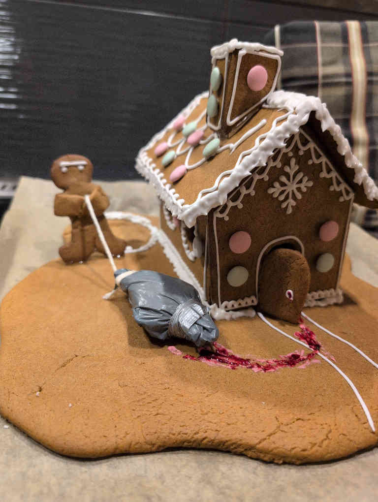 kuva piparkakkutalosta jonka pihalla raahataan ruumista